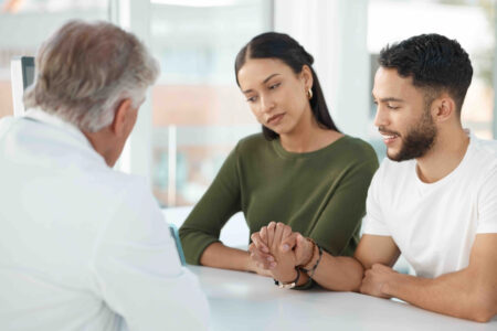 Young couple sits with obstetrician during a fertility consultation in the clinic