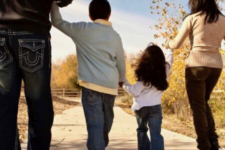 BIPOC family of four holding hands walking away